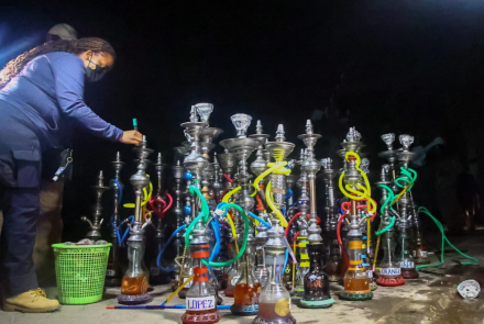 An officer parades the confiscated shisha bongs outside Yejoka Garden Restaurant in Kilimani, Nairobi on December 22, 2023 when the Authority led by the CEO Dr. Anthony Omerikwa, MBS, raided the entertainment joint 
