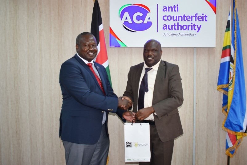 NACADA CEO Dr. Anthony Omerikwa, MBS, hands a gift hamper to the CEO of the Anti-Counterfeit Authority Dr. Robbi Mbugua